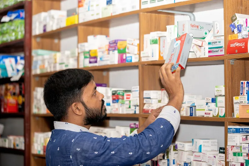 A pharmacist arranging medicines on the shelves of a neighbourhood chemist shop